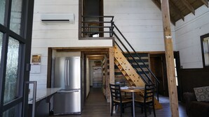 A wooden interior with a kitchen, dining area, and a staircase. - The Barn at Reed | Hot Tub + Horse Friendly (Reeds)