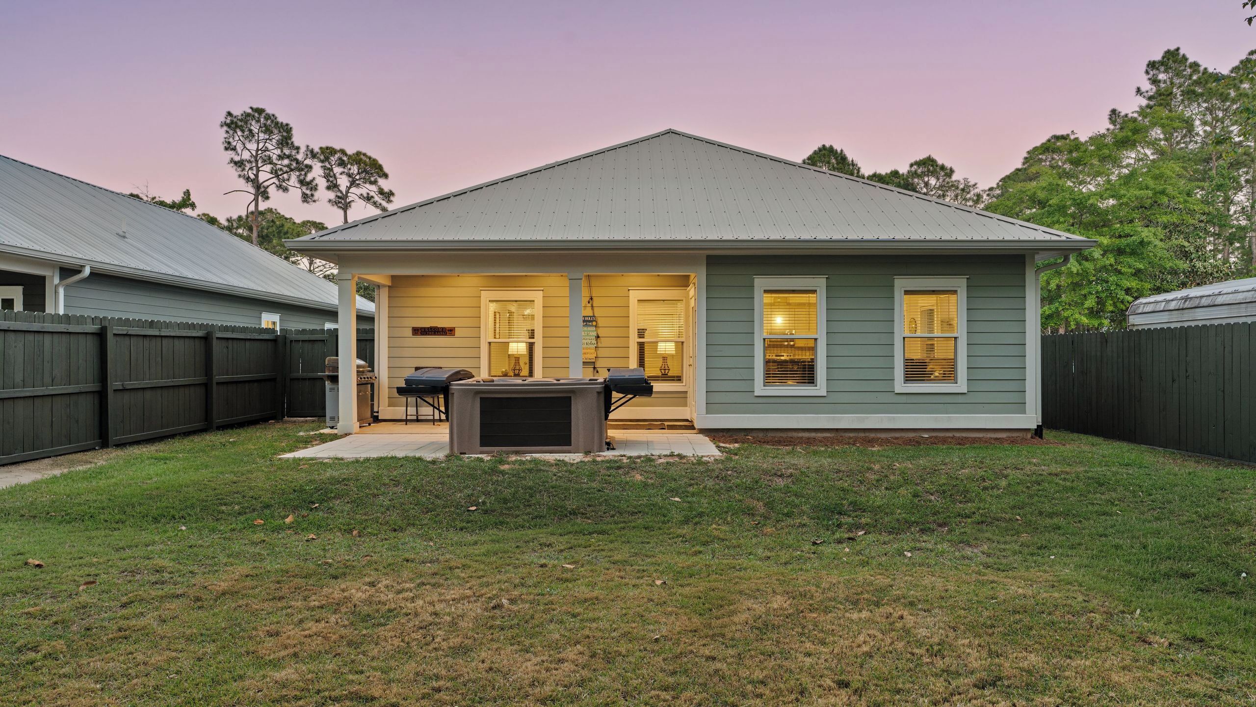 A single-story house with a covered patio, a grill, and a fenced backyard.