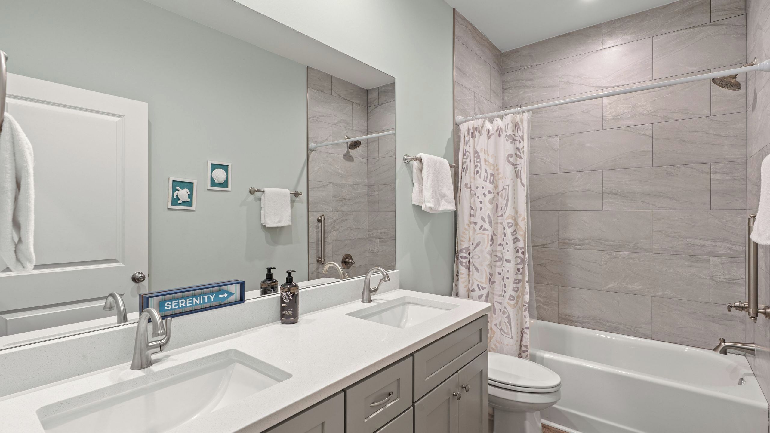 A bathroom with a double sink, a toilet, a bathtub, and a shower.