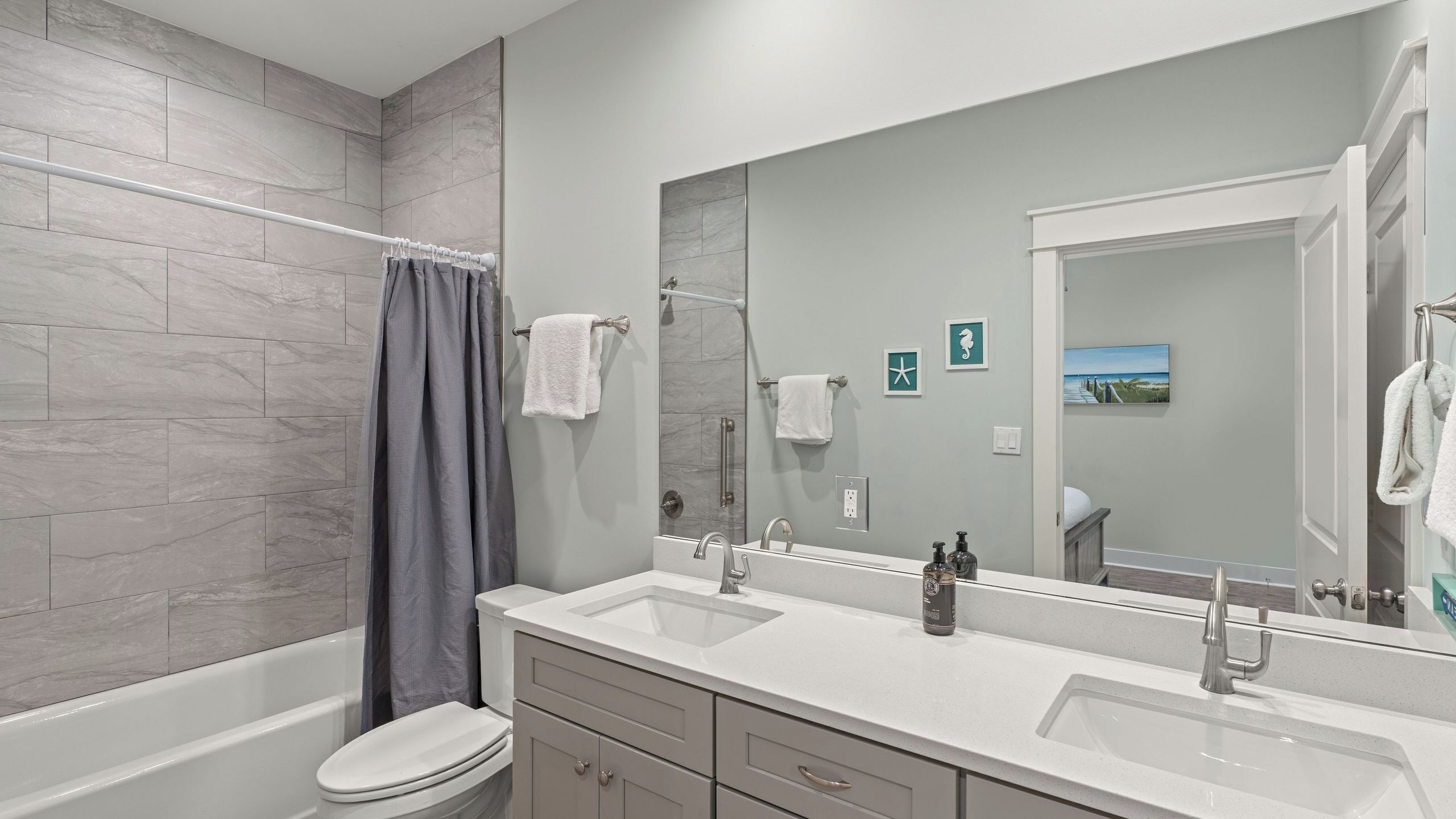 A modern bathroom with a bathtub, toilet, and two sinks.