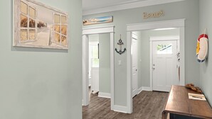 A hallway with a wooden floor, a door with a window, and a wall with a 'Beach' sign. - Central Pines by Avantstay 30A Wooded Retreat Hot Tub + Private Yard Near Beaches (Santa Rosa Beach)