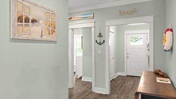 A hallway with a wooden floor, a door with a window, and a wall with a 'Beach' sign.