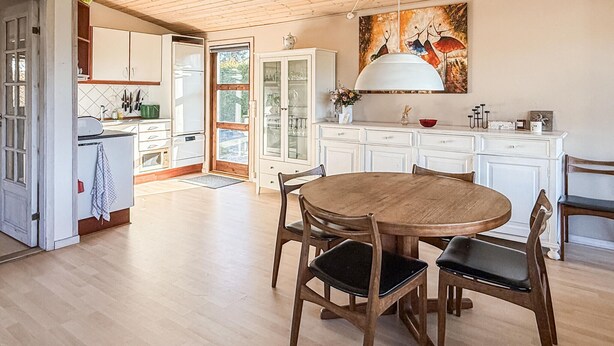 A kitchen with white cabinets, a dining table with chairs, and a large window.