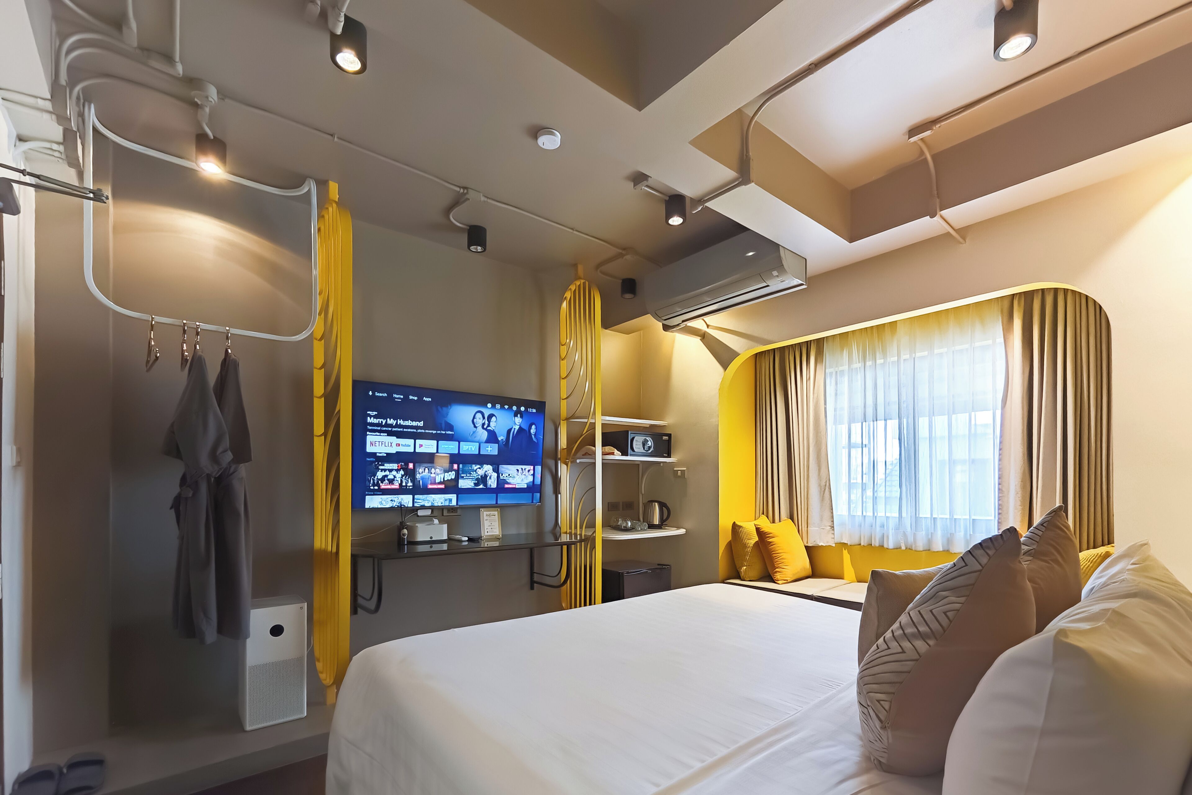 A hotel room with a bed, a TV, a wardrobe, and a window with curtains.