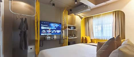A hotel room with a bed, a TV, a wardrobe, and a window with curtains.