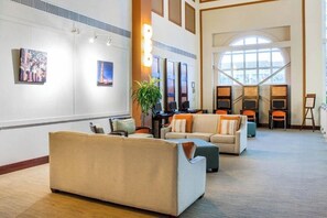 A spacious lobby with a high ceiling, a large arched window, and a seating area with sofas and armchairs. - Cozy 1-bedroom condo with AC in fabulous Oranjestad (Oranjestad)