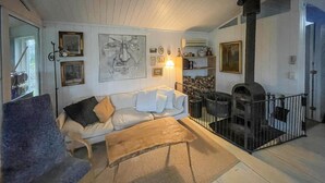 Una sala de estar con un sofá, una mesa de centro, una chimenea y una escalera que sube a un nivel superior.