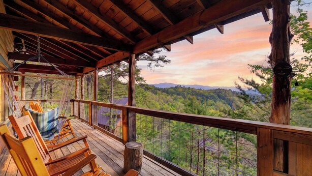 A wooden deck with benches, a hammock, and a view of a forested mountain range. - Maggie's Cabin by Avantstay Hot Tub + Fire Pit + Mountain Views + All-wood Cabin Near National Park (Townsend)