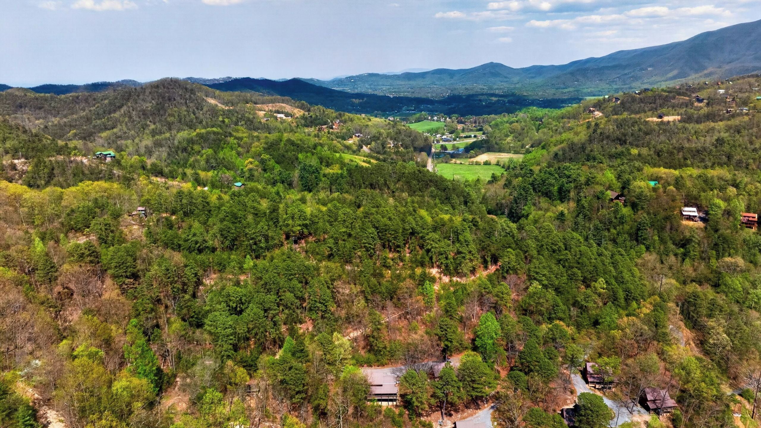 A mountainous landscape with scattered houses and a clear view of the valley.