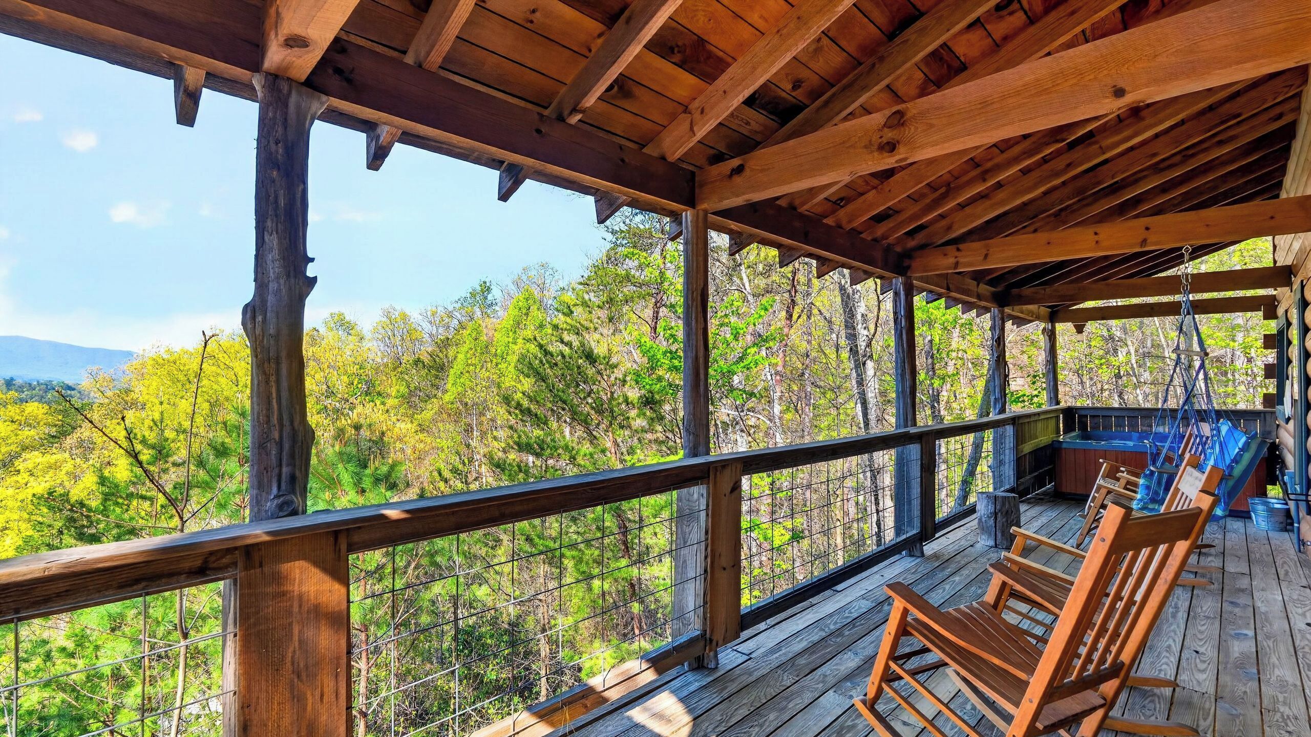 A wooden deck with a railing, overlooking a forested area.
