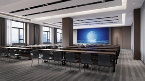 A modern conference room with rows of tables and chairs, large windows, and a projection screen displaying a globe. - Mehood Lestie Hotel Lanzhou Wanda Plaza (Lanzhou)