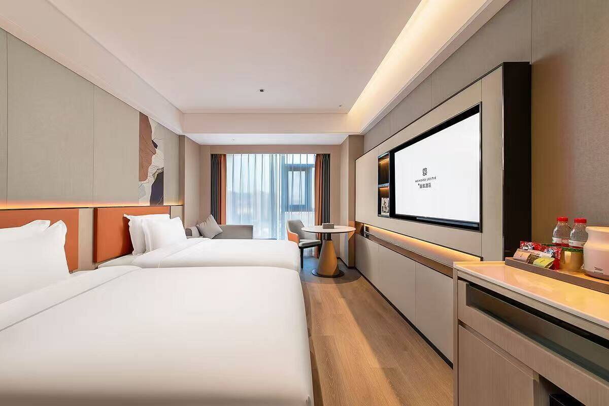 Quarto de hotel com duas camas, uma mesinha, televisão e minibar.