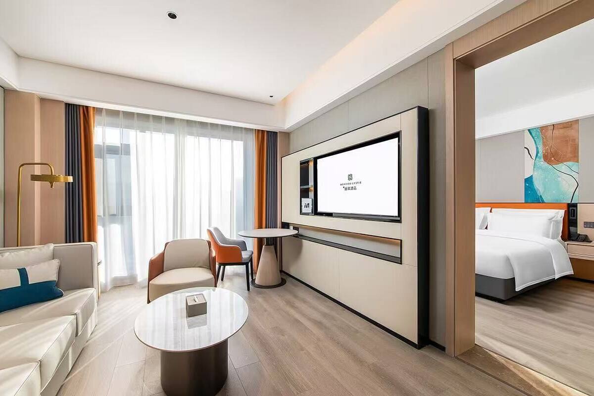 Quarto de hotel com cama, televisão, sofá, mesa de centro e cadeira.