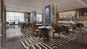 A modern hotel lobby with a geometric patterned floor, seating areas, and a view of the cityscape through large windows. - Mehood Lestie Hotel Lanzhou Wanda Plaza (Lanzhou)