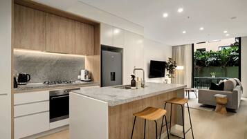 A modern kitchen with a central island, built-in appliances, and a seating area with a sofa and bar stools.
