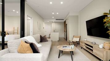 A modern living room with a sofa, coffee table, TV, and a plant.