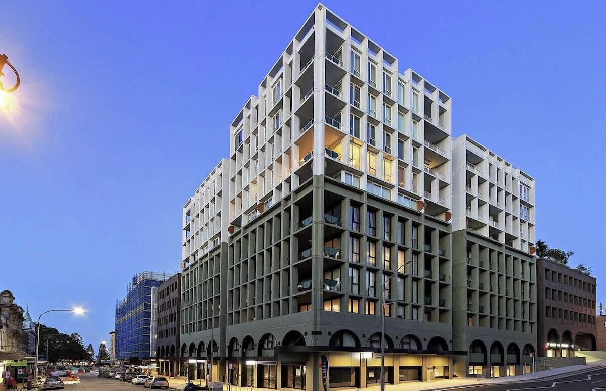 A multi-story hotel with a grid-like facade, balconies, and a ground-level entrance.