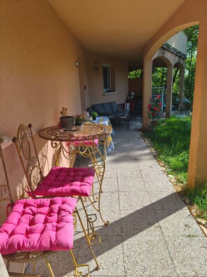 Un área de estar al aire libre cubierta con una mesa, sillas, un sofá y vistas a un jardín.