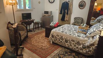 Une chambre à coucher comprenant un lit, un bureau, une chaise, un téléviseur, une horloge et un miroir.
