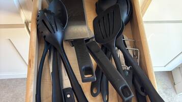 A drawer containing various kitchen utensils including spatulas, a grater, and a pair of scissors.