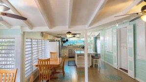 Une cuisine avec un coin repas, des chaises en bois, un ventilateur de plafond et une vue par la fenêtre.