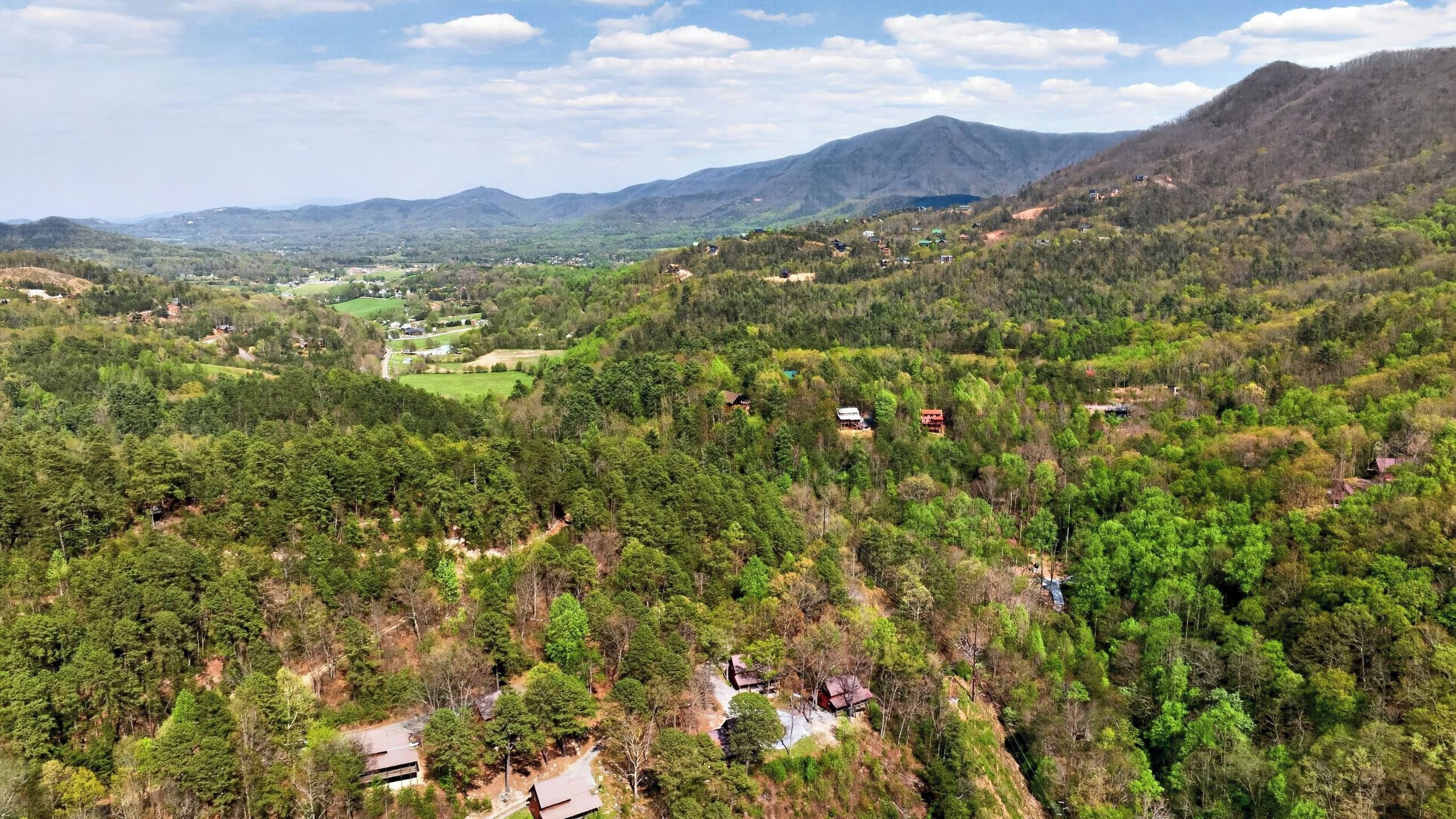 A mountainous landscape with scattered houses and dense forests.