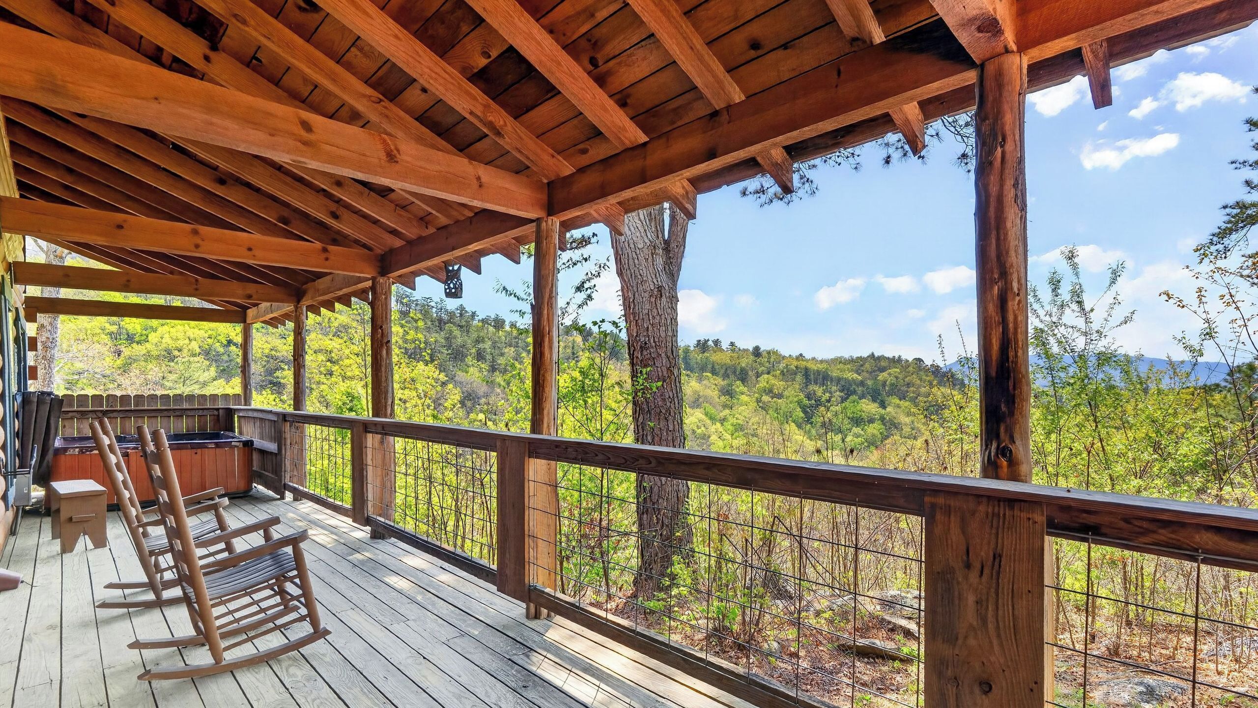 Un terrazzo in legno con poltrone a dondolo e vista su un paesaggio boschivo.