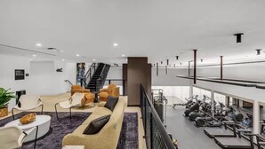 Un interior modern amb zona de seients, escala i equipament esportiu.