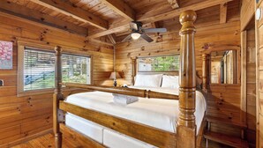 A wooden cabin room with a four-poster bed, a ceiling fan, and a window with blinds. - Isaiah's Cabin by Avantstay Private Hot Tub + Fire Pit + Mountain Views Near Smokies + Townsend (Townsend)