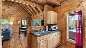 A wooden cabin interior with a kitchen, dining area, and a living room. - Isaiah's Cabin by Avantstay Private Hot Tub + Fire Pit + Mountain Views Near Smokies + Townsend (Townsend)