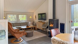 Una sala acogedora con sofá, sillón, televisión y chimenea de leña.
