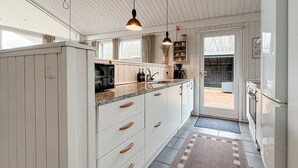 Una cocina con armarios blancos, microondas, cafetera y un fregadero.