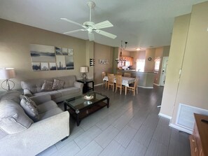 A living room with a sofa, coffee table, and dining area with chairs and a table. - Emerald Island Resort Double Beds Pet Friendly (Kissimmee)