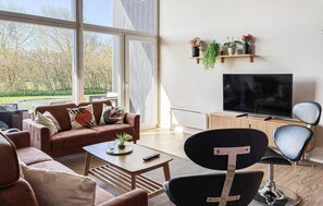 A modern living room with a sofa, coffee table, TV, and a chair. - Lovely home in Hemmet with sauna (Hemmet)