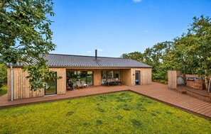 A modern wooden house with a tiled roof, a deck, and a grassy yard. - Beautiful home in Skjern with sauna (Skjern)