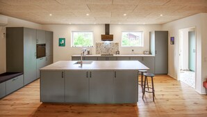 A modern kitchen with a central island, built-in appliances, and a view of greenery outside. - Beautiful home in Skjern with sauna (Skjern)