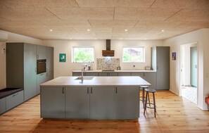 A modern kitchen with a central island, built-in appliances, and a view of greenery outside. - Beautiful home in Skjern with sauna (Skjern)