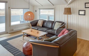 A modern living room with a leather sofa, a wooden coffee table, and a wicker lamp. - Gorgeous home in Hvide Sande with sauna (Hvide Sande)