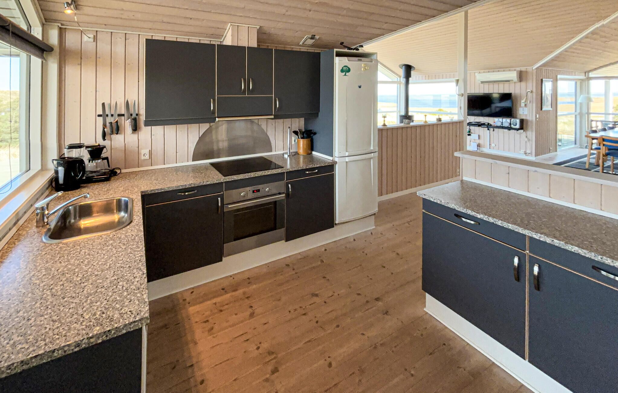 Een moderne keuken met donkere kastjes, een roestvrijstalen spoelbak en een ingebouwde oven.