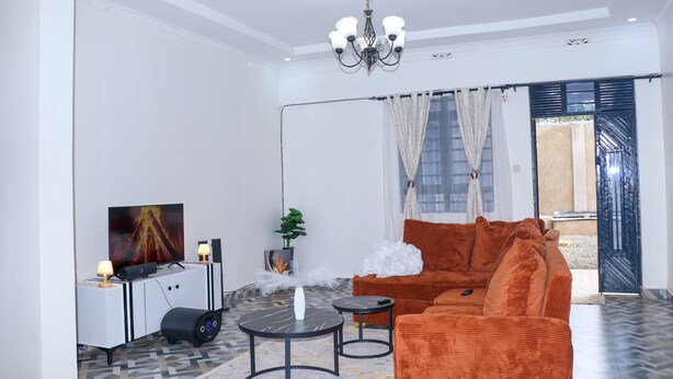 Una sala de estar moderna con sofá, televisor y candelabro.