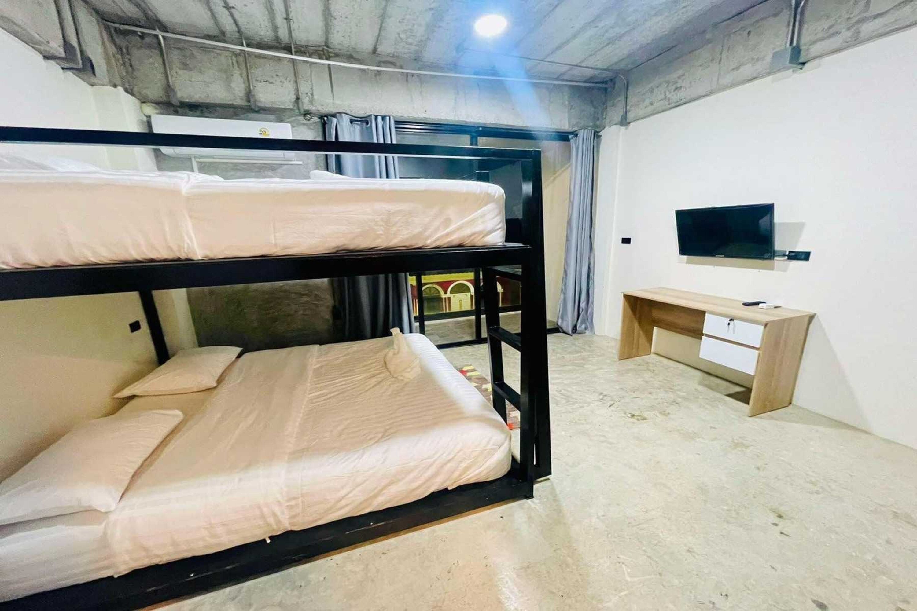 Een slaapkamer met stapelbed, bureau en televisie.