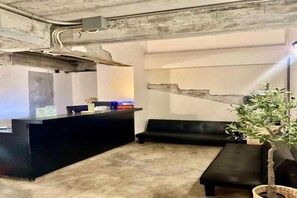 A reception area with a black counter, a seating area with a black sofa, and a plant. - Collection O Lamoon Patong (Patong)