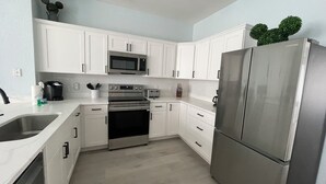 A modern kitchen with white cabinets, stainless steel appliances, and a built-in microwave. - Renovated 3 Bedroom Town Home with Pool in Windsor Hills (Kissimmee)