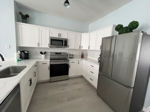 A modern kitchen with white cabinets, stainless steel appliances, and a built-in microwave. - Renovated 3 Bedroom Town Home with Pool in Windsor Hills (Kissimmee)