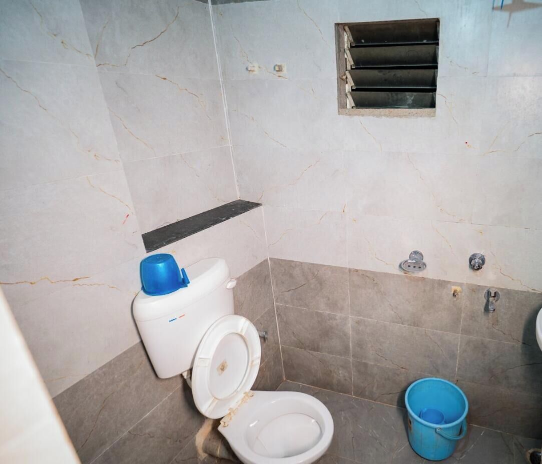 Et badeværelse med toilet, en blå balje og en beskadiget væg.