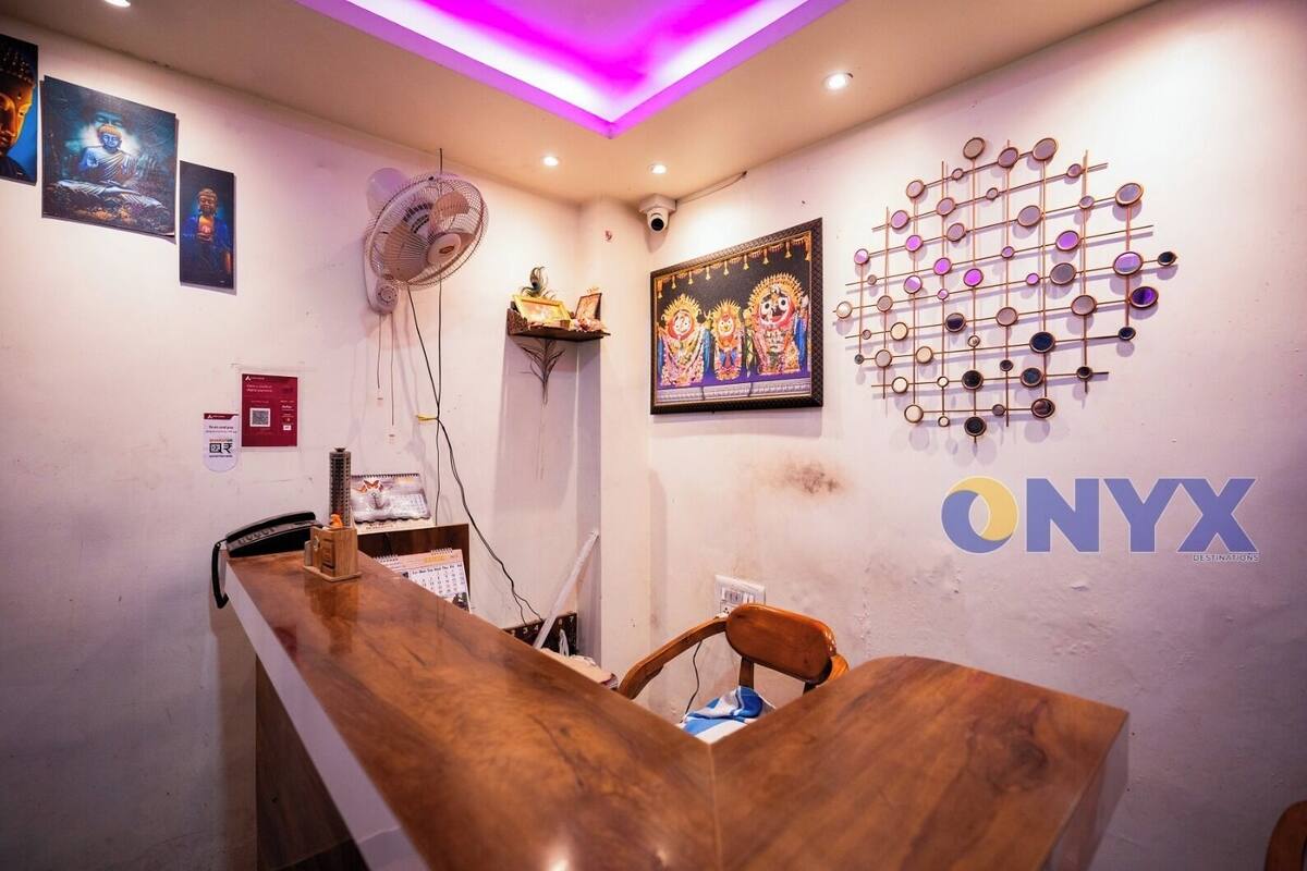 A reception area with a wooden reception desk, a wall-mounted fan, framed artwork, and a decorative wall piece.