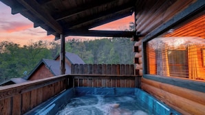 A wooden cabin with a hot tub, a wooden deck, and a view of the forest. - Sónyah's Cabin by Avantstay Hot Tub + Deck + Firepit + Mountain Views Mins to Downtown (Townsend)