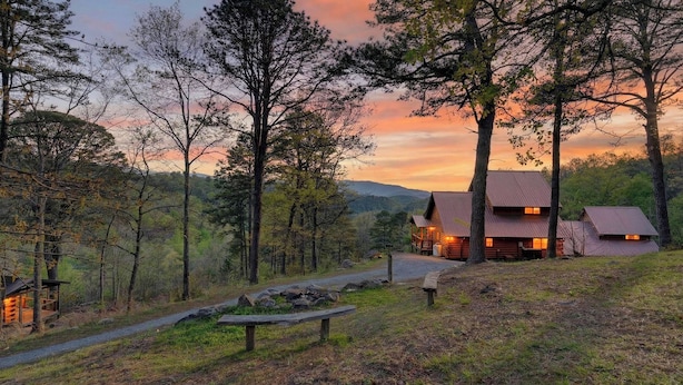 A cabin with a metal roof, surrounded by trees and a gravel path. - Sónyah's Cabin by Avantstay Hot Tub + Deck + Firepit + Mountain Views Mins to Downtown (Townsend)