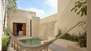 Un'amaca su una piscina, una porta e un muro in pietra.