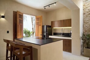 A modern kitchen with a central island, wooden cabinets, and a built-in stove. - 2 BR Oasis in Centro w/ Private Pool - Casa Kiik (Centro)
